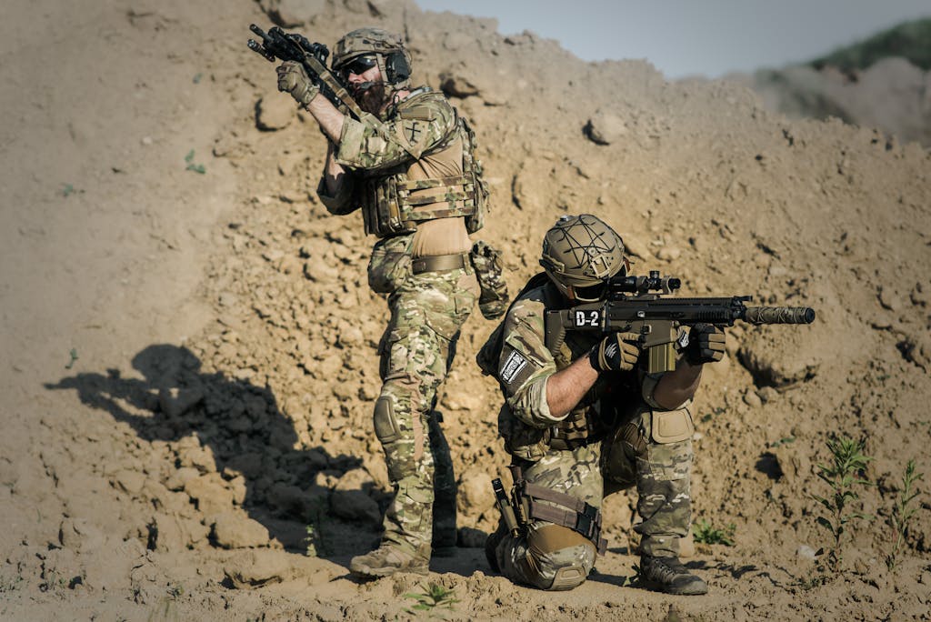 Two soldiers in camo engage in tactical training in a desert environment.